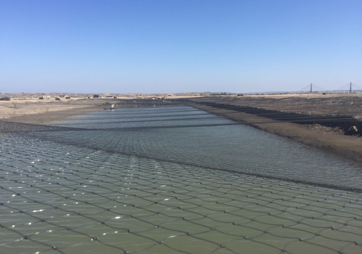 View of an aquaculture area with a black net covering the entire water zone.