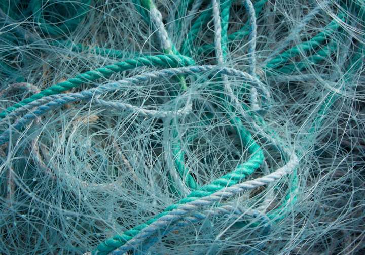 Fishing nets made of monofilament in shades of green and blue, interwoven with thick ropes in shades of green and blue.
